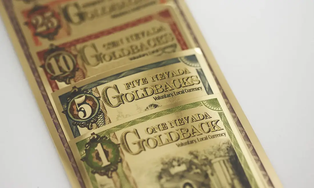 Nevada Goldbacks arranged beside Nevada mining imagery